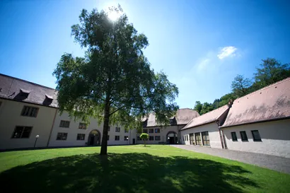 Torbogen aus Sandstein am Zugang zum Klostergelände, beschattet von Bäumen